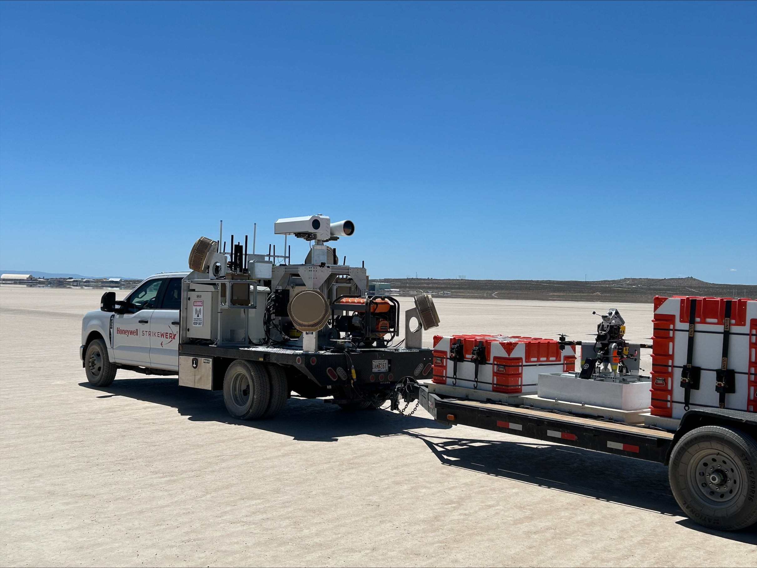 A Honeywell-branded truck equipped with scientific instruments and trailer containers in a wide-open field setting.